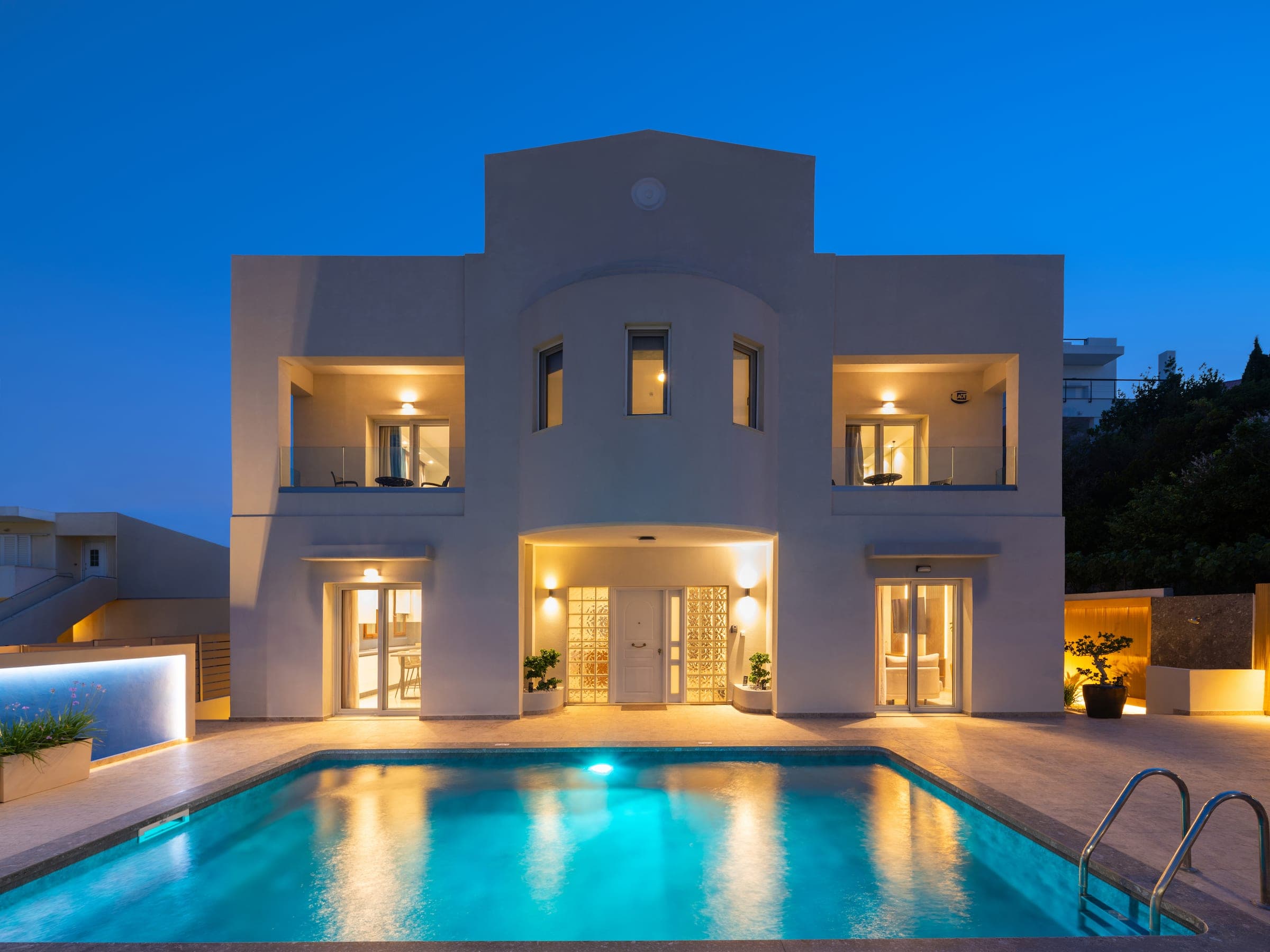 Lumina Villa at dusk, its windows lit and the private pool glowing turquoise in the foreground.